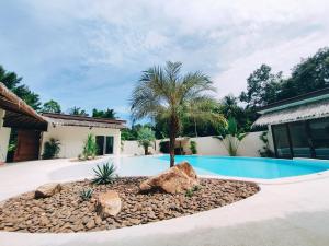 a swimming pool with a palm tree in a yard at Villa Baan Naí Pã in Ban Tai
