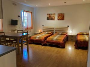 a bedroom with two beds and a table and a dining room at Residence Stefania Cavasso Nuovo in Cavasso Nuovo