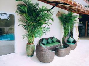 um grupo de palmeiras em cadeiras de vime e uma piscina em Villa Baan Naí Pã em Baan Tai