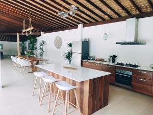 a kitchen with a white counter and stools at Villa Baan Naí Pã in Baan Tai