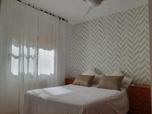 een slaapkamer met een wit bed met 2 kussens bij Casa con gran jardín y unas preciosas vistas in Teià