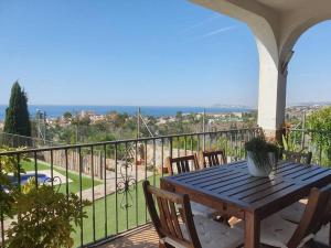 een houten tafel en stoelen op een balkon met uitzicht bij Casa con gran jardín y unas preciosas vistas in Teià