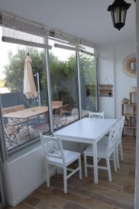 una mesa y sillas blancas en una habitación con ventana en Le petit Sud, en Carqueiranne