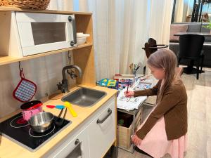 a young girl standing in a kitchen preparing food at Centennial Nexus Hotel Tallinn in Tallinn