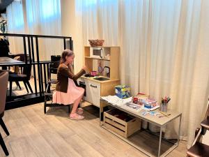 a young girl standing in a small kitchen with a table at Centennial Nexus Hotel Tallinn in Tallinn