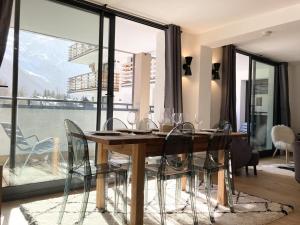 a dining room table with chairs and a large window at Chamonix Praz Vue Mt Blanc Piscine in Chamonix-Mont-Blanc