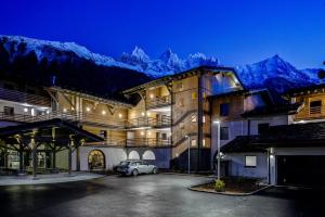 een gebouw met een auto geparkeerd op een parkeerplaats met bergen bij Chamonix Praz Vue Mt Blanc Piscine in Chamonix-Mont-Blanc