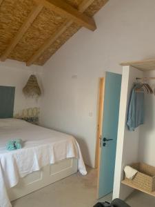 1 dormitorio con cama blanca y puerta azul en Além do Tejo, en Arraiolos