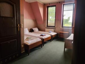two beds in a room with two windows at Hostel Bialoleka - Darmowy parking, szybkie Wifi! in Warsaw