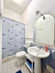 baño con aseo y lavabo con pájaros en la pared en Casa Vacanze Longo, en Santa Marina Salina