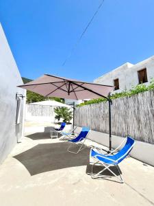 eine Gruppe Stühle und ein Sonnenschirm auf einer Terrasse in der Unterkunft Casa Vacanze Longo in Santa Marina Salina