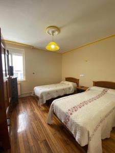 1 dormitorio con 2 camas, ventana y suelo de madera en PENSIÓN SANTA CLARA en Pontevedra