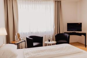 une chambre d'hôtel avec un lit, deux chaises et une télévision dans l'établissement Fährhaus Kollmar, à Kollmar