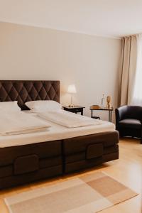 duże łóżko w sypialni z krzesłem w obiekcie Fährhaus Kollmar w mieście Kollmar