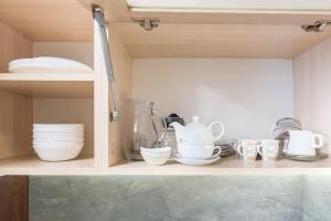 a cabinet filled with dishes and cups on a shelf at Stylish apartment on Bregalnitsa str in Varna City