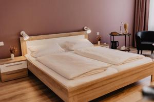 - une chambre avec un grand lit en bois et des draps blancs dans l'établissement Fährhaus Kollmar, à Kollmar