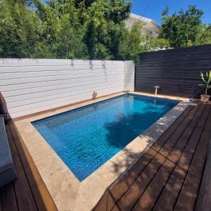 a swimming pool in a backyard with a wooden deck at La Cas'Aline in La Saline les Bains