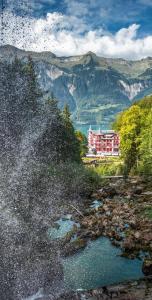 a large building in the distance with a river in front at Hotel Wildbach Brienz in Brienz