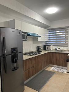 a kitchen with a stainless steel refrigerator and wooden cabinets at Cancun 16, South 6 Person 3 Rooms 15 min Airport 20 to Beach in Cancún