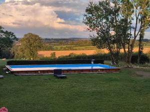 a large blue swimming pool in a grass field at Maison d'hôtes La Roulotte des 4 Saisons in Sazeray