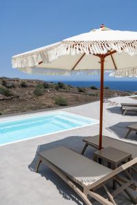 a white umbrella and chairs next to a swimming pool at Alegria by Casa Sigalas in Oia