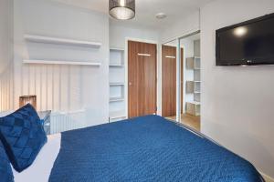 um quarto com uma cama azul e uma televisão de ecrã plano em Host & Stay - London Avenue em Glasgow