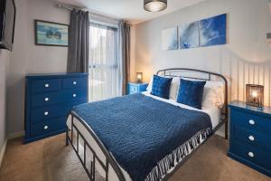 a bedroom with a bed with blue dressers and a window at Host & Stay - London Avenue in Glasgow