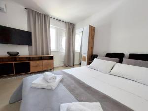 een slaapkamer met een groot wit bed en handdoeken bij Studio apartment SeaDream - 50 meters from the sea in Brodarica