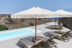 een groep stoelen en parasols naast een zwembad bij Alegria by Casa Sigalas in Oia