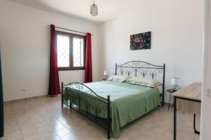 1 dormitorio con 1 cama con manta verde y ventana en Villetta L'Ajara, en Ortelle
