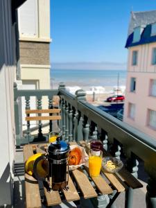 a table with food and drinks on a balcony at Villa Adèle, Sauna et Balcon vue Mer - Appt 03 in Mers-les-Bains