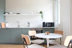 cocina con mesa blanca y sillas en Villa Adèle, Sauna et Balcon vue Mer - Appt 03 en Mers-les-Bains
