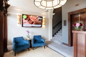 a lobby with two blue chairs and a television on the wall at Tower Residences by Blue Orchid in London