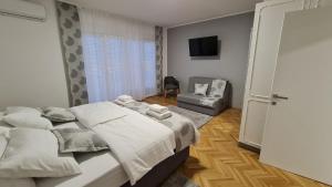 1 dormitorio con 1 cama, 1 silla y TV en Apartman Magnolija en Rijeka