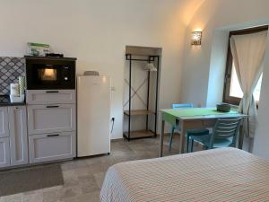 Habitación con cama y cocina con nevera y mesa. en Stazzu nuraghe Mannucciu, en Rena Majore