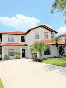 a white house with palm trees in the driveway at Gone 2 Florida Vacation Homes in Orlando