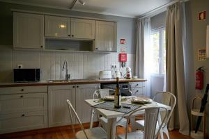 una cocina con armarios blancos y una mesa con sillas. en Materramenta, en Biscoitos