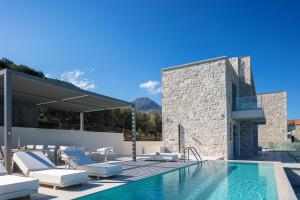 a villa with a swimming pool and lounge chairs at Petras Luxury Villas in Falasarna