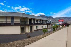 a building on a street with mountains in the background at Canadas Best Value Inn & Suites Kamloops in Kamloops