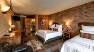 1 dormitorio con 2 camas y pared de ladrillo en Ndlovu Lodge, en Pretoria