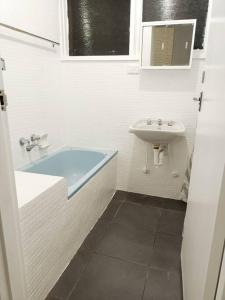 a white bathroom with a sink and a bath tub at PROMO 2-Bedroom Villa Next to Train Station, FREE PARKING in Melbourne
