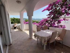 a patio with a table and chairs and purple flowers at Apartment Light House in Dobra Voda
