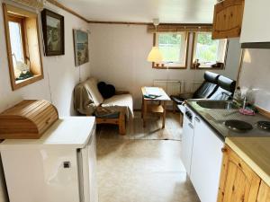 a small kitchen and living room with a couch at Red little cottage located in the forest and next to a small lake in Örsjö