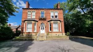 a brick house with a large driveway in front of it at Sleeps 20 Stunning Ashton Mansion in Ashton under Lyne