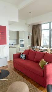 a living room with a red couch and a kitchen at Smartflats - Central Antwerp in Antwerp