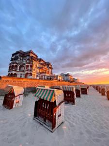 a row of beach chairs on the beach with a building at meergut HOTELS in Kühlungsborn