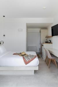a white bedroom with a bed and a table at Alegria by Casa Sigalas in Oia