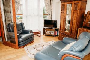 uma sala de estar com um sofá e uma cadeira e uma televisão em The Barn B&B em Margam