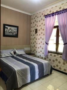 バンドンにあるVilla Bukit Punclutのベッドルーム1室(紫色のカーテンが付いた大型ベッド1台付)