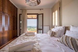a large white bed in a bedroom with a window at Villa Sarri by Sarris Winery in Metaxáta